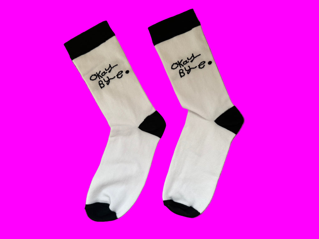 Black and white socks with Okay Bye written on each sock above the ankle